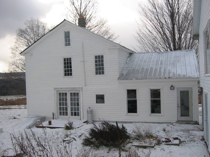 Back of farmhouse with the garage forming the backdrop for the backyard.