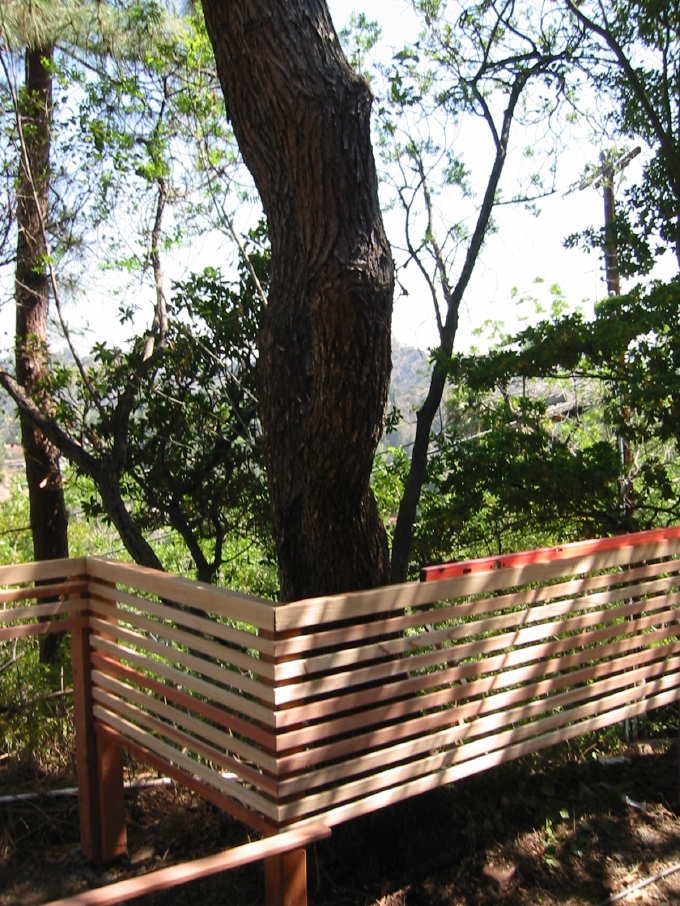 The new railing under construction, a ribbon of redwood that bends around trees 