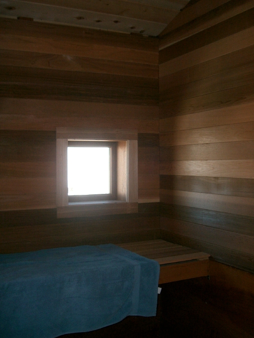 Interior of sitting area of sauna with narrow red cedar on walls and wide cedar 