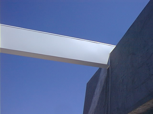 The laminated structural beam, wrapped in white sheet metal, intersecting the ti